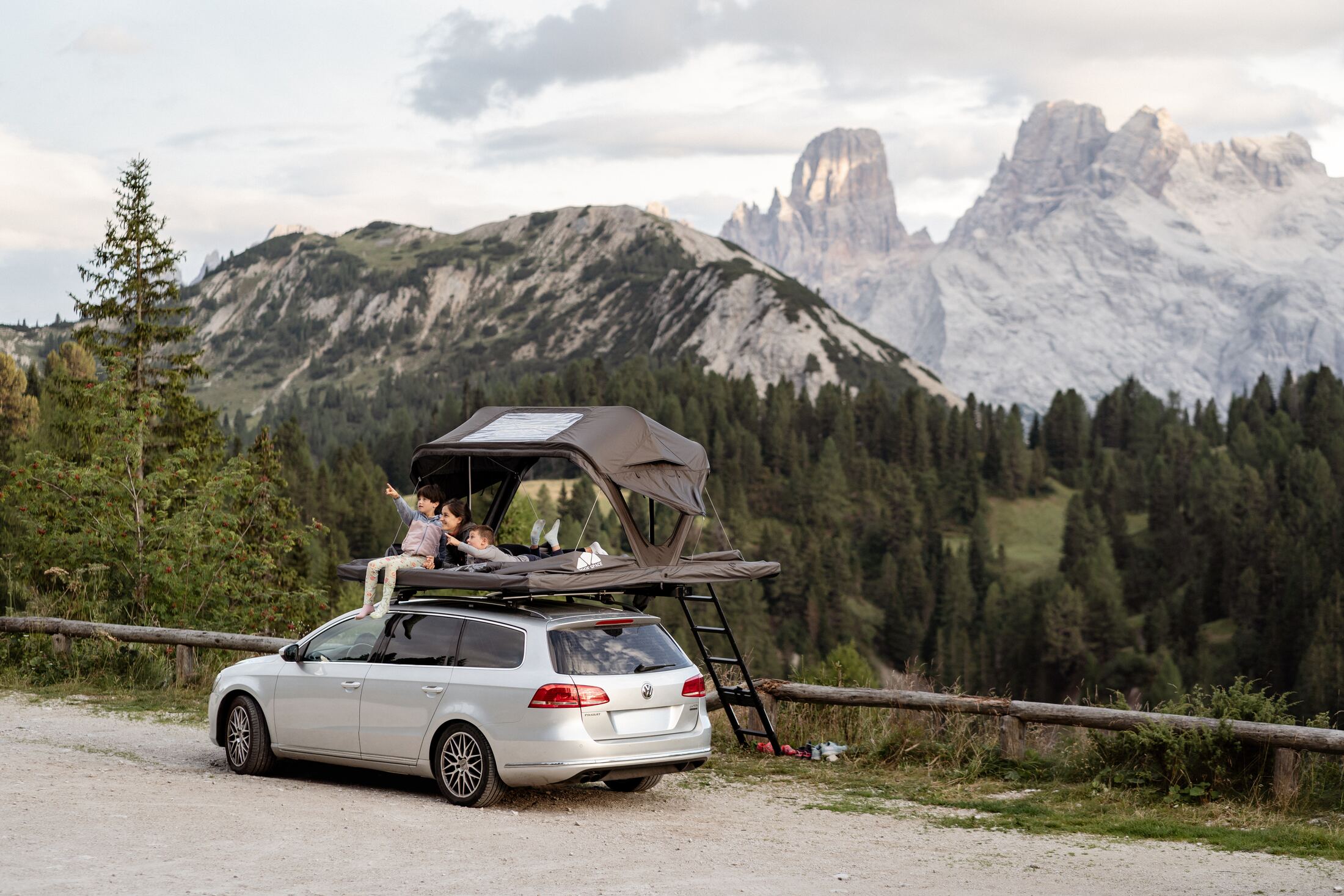 Familie im Roof Space Dachzelt auf dem Kombi vor den Dolomiten