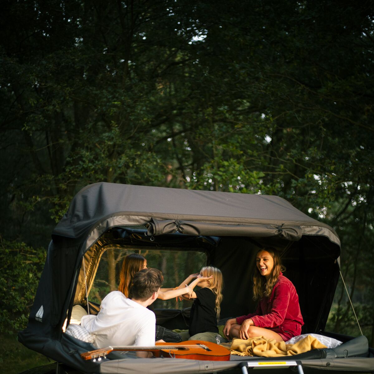 Paar im geöffneten Roof Space 4 Dachzelt am Waldrand