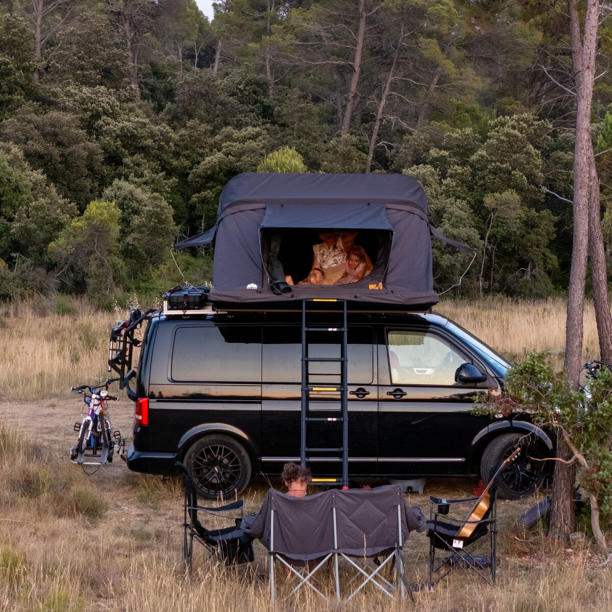 Van mit geöffnetem Roof Space 4 Dachzelt auf einer Waldlichtung
