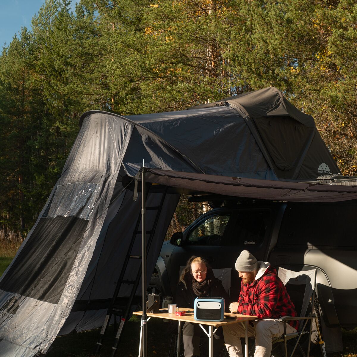 Paar sitzt am Campingtisch unter dem Vorzelt Light Base